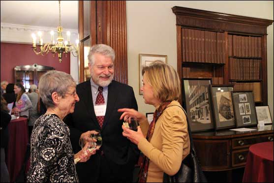 UUA Financial Advisor Larry Ladd (center) visits with former UUA trustee Eva Marx and Elizabeth McGregor, former chair of the General Assembly Planning Committee, at the Feb. 21 Beacon Benediction ceremony at 25 Beacon Street; behind them, photographs of former homes of the American Unitarian Association are displayed in Greeley Library